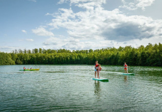 Folk nyder stand up paddleboarding og kajaksejlads på en sø ved The TreeLoft by YourNature i Belgien.
