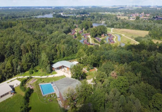 Aerial view of The TreeLoft by YourNature in Belgium, surrounded by forest, a pool, and nearby lodges.