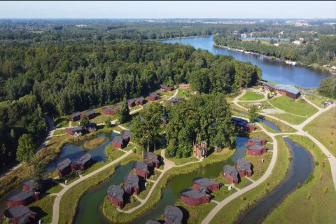Aerial view of tree houses and ponds at The TreeLoft by YourNature in Belgium, surrounded by forest and river.