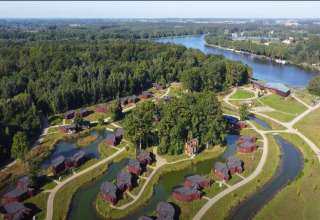 Aerial view of tree houses and ponds at The TreeLoft by YourNature in Belgium, surrounded by forest and river.