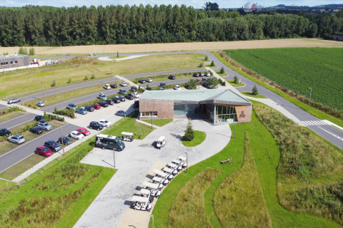 Aerial view of a glamping accommodation with a main building, parking lot, greenery, and golf carts.