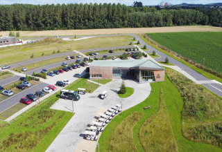 Aerial view of a glamping accommodation with a main building, parking lot, greenery, and golf carts.
