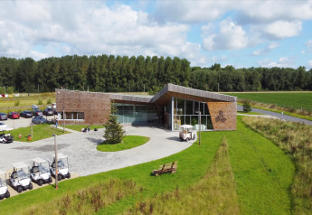Hébergement glamping avec bâtiment en bois moderne, voiturettes de golf, parking et nature verdoyante ensoleillée.