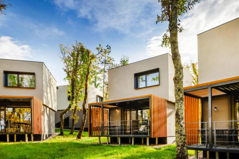 Moderne Aminess Gaia Green Villas Njivice - Bungalow Pinus 4 plus 2, omgeven door bomen en natuur.