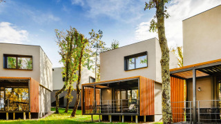 Moderne Aminess Gaia Green Villas Njivice - Bungalow Pinus 4 plus 2, omgeven door bomen en natuur.