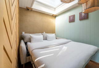 Dormitorio acogedor en TreeLoft con cama doble, tragaluz y decoración inspirada en la naturaleza.