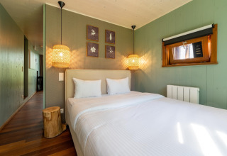 Dormitorio en The TreeLoft de YourNature, con cama doble, lámparas colgantes y paredes verdes.