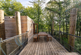 Terraza exterior de madera en The TreeLoft por YourNature, rodeada de árboles altos y diseño moderno.
