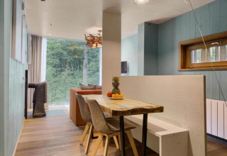 Moderner Essbereich im Baumhaus mit Waldblick, Holztisch und gemütlicher, naturnaher Einrichtung.
