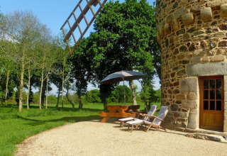 Zona exterior en la casa de naturaleza 'Ancient windmill Gommenec'h' en Francia, con mesa y tumbonas.