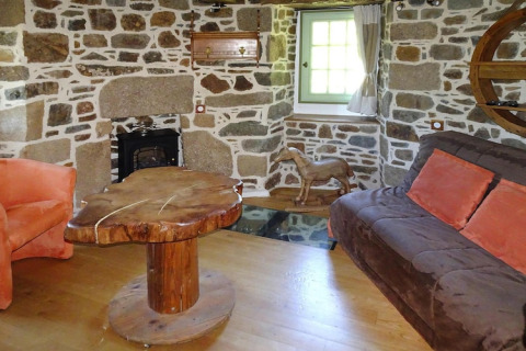 Salón en antiguo molino de viento en Gommenec'h, Francia, con paredes de piedra y mesa rústica de madera.