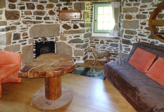 Salón en antiguo molino de viento en Gommenec'h, Francia, con paredes de piedra y mesa rústica de madera.