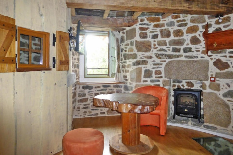 Rustic living area with stone walls and wood furniture in Ancient windmill Gommenec'h, France.