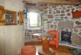 Rustic living area with stone walls and wood furniture in Ancient windmill Gommenec'h, France.