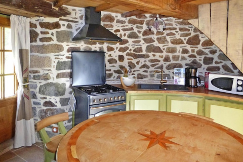 Cucina rustica nella vecchia mulino a vento Gommenec'h, Francia, muri in pietra e tavolo rotondo.