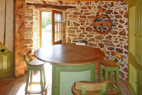 Acogedora cocina en el antiguo molino de viento Gommenec'h en Francia, con paredes de piedra y muebles verdes.