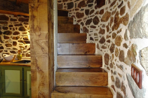 Scala in legno massiccio e muri in pietra in un antico mulino a vento a Gommenec'h, Francia.