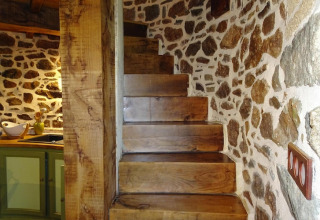 Scala in legno massiccio e muri in pietra in un antico mulino a vento a Gommenec'h, Francia.
