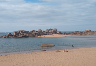 Sandy beach with rocky formations and water at Ancient windmill Gommenec'h nature house in France.
