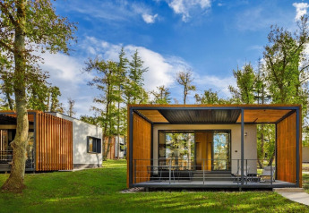 Moderne bungalow med trædetaljer og stor terrasse omgivet af grønne træer i Aminess Gaia Green Villas, Kroatien.