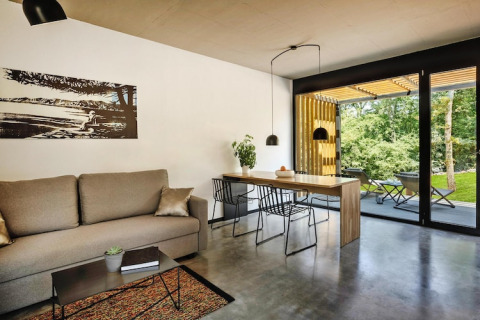 Moderne woonkamer in Aminess Gaia Green Villas Njivice, Kroatië, met bank, eettafel en uitzicht op de natuur.
