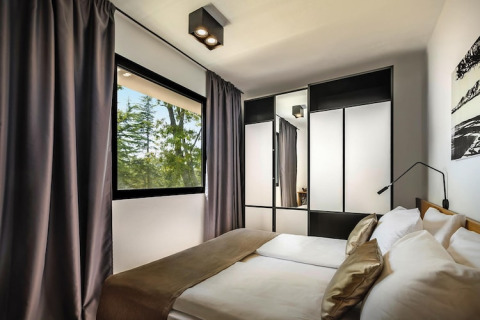 Moderne slaapkamer met tweepersoonsbed, spiegelkast en groot raam bij Aminess Gaia Green Villas, Kroatië.