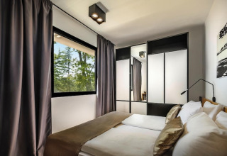 Moderne slaapkamer met tweepersoonsbed, spiegelkast en groot raam bij Aminess Gaia Green Villas, Kroatië.