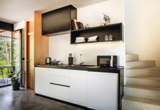 Moderne keuken bij Aminess Gaia Green Villas Njivice met witte kasten en zwarte accenten naast de trap.