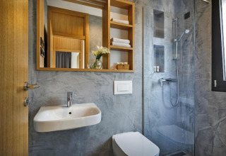 Moderne badkamer met spiegel, wastafel, toilet en douche bij Aminess Gaia Green Villas in Kroatië.