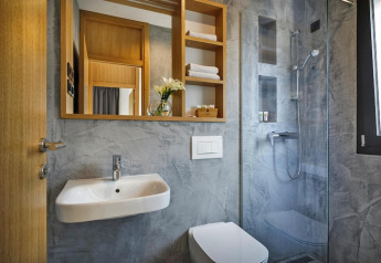 Moderne badeværelse med spejl, håndvask, toilet og bruseniche på Aminess Gaia Green Villas i Kroatien.