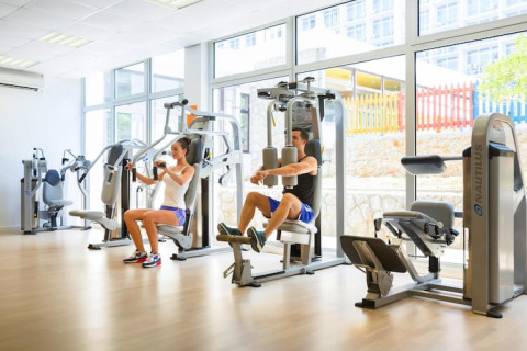 Sportschool met grote ramen, twee mensen trainen op toestellen bij Aminess Gaia Green Villas Njivice, Kroatië.