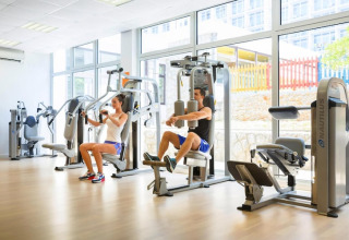 Sportschool met grote ramen, twee mensen trainen op toestellen bij Aminess Gaia Green Villas Njivice, Kroatië.