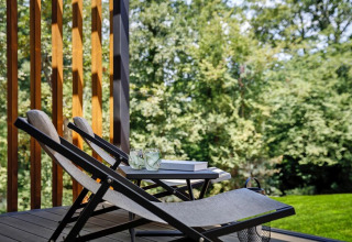 Twee ligstoelen en een tafel met drankjes op een terras met uitzicht op groene bomen in Kroatië.