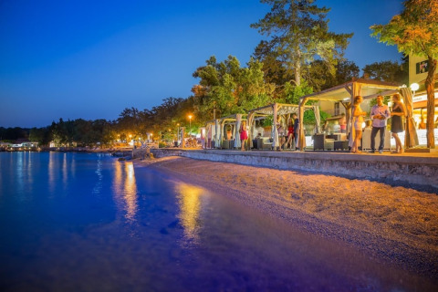 Avondsfeer bij Aminess Gaia Green Villas Njivice, Kroatië, waar gasten ontspannen aan het strand.