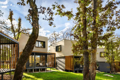 Moderne bungalows omringd door bomen bij Aminess Gaia Green Villas Njivice, Kroatië, op een zonnige dag