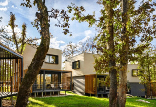 Moderne bungalows omringd door bomen bij Aminess Gaia Green Villas Njivice, Kroatië, op een zonnige dag