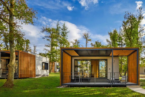 Casa mobile moderna con facciata in legno e terrazza, immersa nel verde in Croazia sotto il cielo blu.