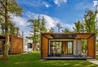 Modern mobiel huis met houten panelen en terras, omringd door bomen en natuur, blauwe lucht in Kroatië.