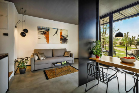 Moderne stacaravan woonkamer en eetgedeelte met grote ramen, stijlvolle inrichting en uitzicht op tuin.