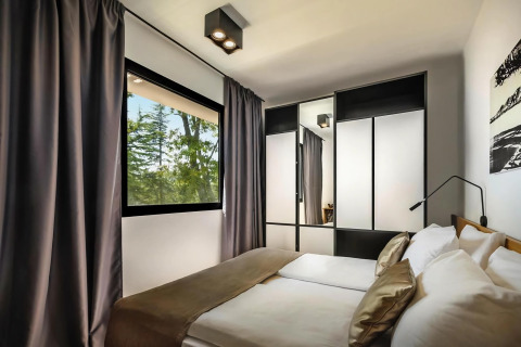 Moderne slaapkamer in Aminess Gaia Green Villas Njivice, Kroatië, met groot raam en ruime kast.
