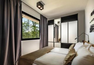 Moderne slaapkamer in Aminess Gaia Green Villas Njivice, Kroatië, met groot raam en ruime kast.