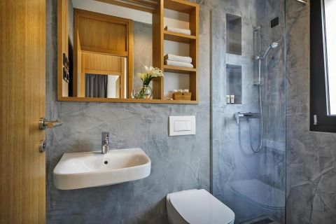 Moderne badkamer met grijze wanden, open douche, wastafel, toilet en houten planken in een mobiel huis in Kroatië.