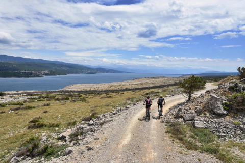 Twee fietsers rijden op een grindpad met uitzicht op zee bij Aminess Gaia Green Villas in Kroatië.