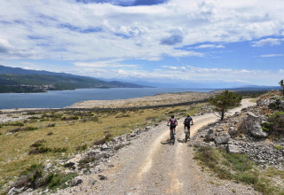 Twee fietsers rijden op een grindpad met uitzicht op zee bij Aminess Gaia Green Villas in Kroatië.