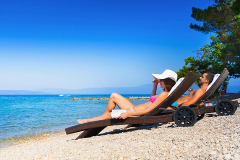 Una coppia si rilassa su lettini sulla spiaggia di Aminess Gaia Green Villas in Croazia.