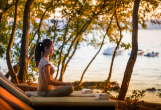 Donna che medita su una terrazza vista mare al tramonto presso Aminess Gaia Green Villas in Croazia.
