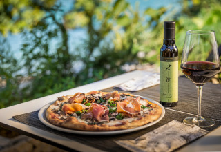 Pizza, olijfolie en een glas rode wijn buiten bij Aminess Gaia Green Villas in Kroatië met groen uitzicht.