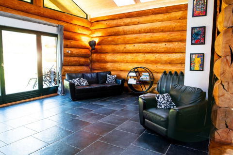 Soggiorno con divani in pelle, decorazioni moderne e pareti di tronchi in uno chalet a Lomnice nad Popelkou, Repubblica Ceca.