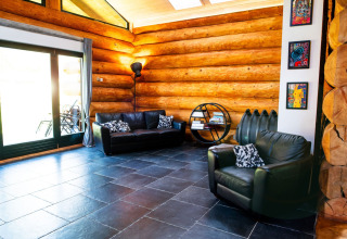 Soggiorno con divani in pelle, decorazioni moderne e pareti di tronchi in uno chalet a Lomnice nad Popelkou, Repubblica Ceca.
