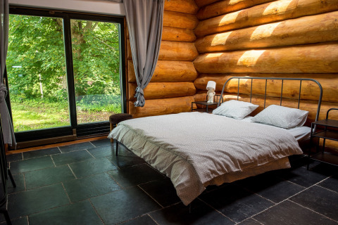 Camera da letto in uno chalet in Repubblica Ceca con letto matrimoniale, pareti in legno e grande finestra.